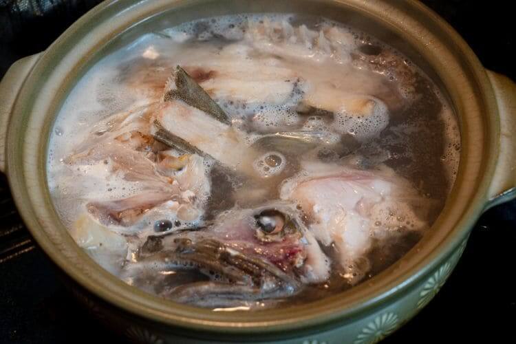 鍋で炊かれている魚のアラ